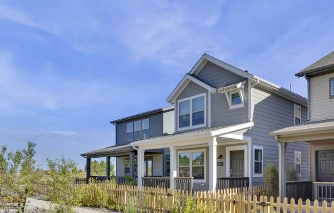 a blue house with white trim and a wooden fence