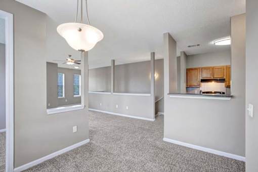 A spacious living room with a kitchenette in the background.