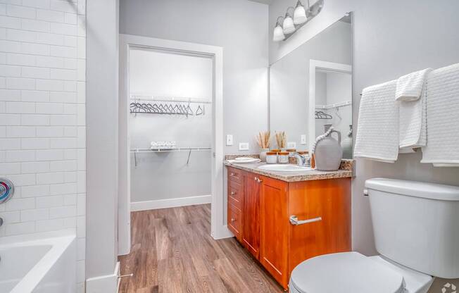A white bathroom with a wooden vanity and a white toilet.