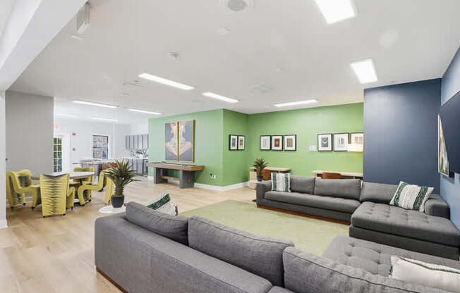 A living room with grey couches and yellow chairs.