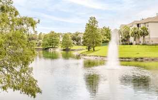 Large community lake with a water feature surrounded by grass and native landscape.