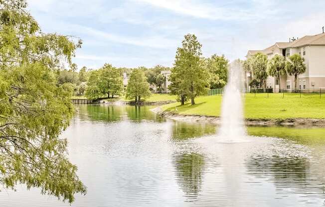 Large community lake with a water feature surrounded by grass and native landscape.