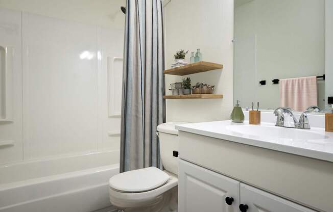 A white bathroom with a toilet, sink, and a shower curtain.