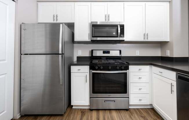 A modern kitchen with a stainless steel refrigerator, black microwave, and black stove top oven.