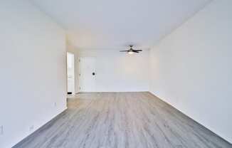 an empty living room with white walls and a ceiling fan