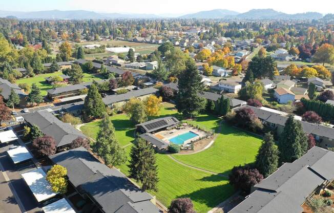 an aerial view of a neighborhood with houses and a green lawn and a pool