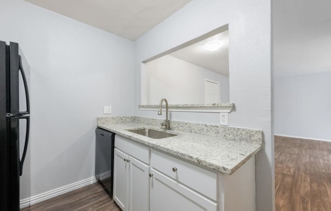 a kitchen with white cabinets and a counter top with a sink