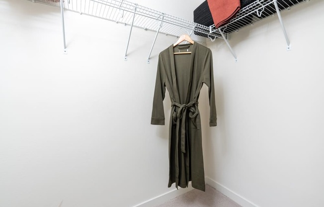 A green dress hanging on a rack in a room.