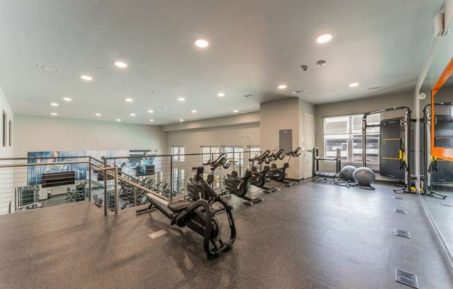 a spacious fitness center with cardio machines and weights at Residences at 3000 Bardin Road, Grand Prairie, TX, Texas, 75052