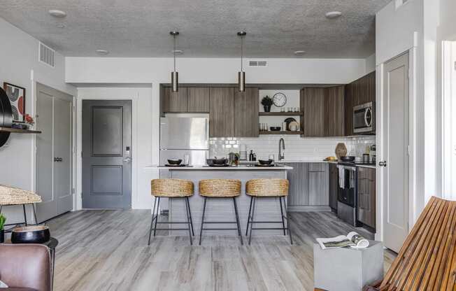 Shot of kitchen and front door, wood tone floors, and designed furnishings