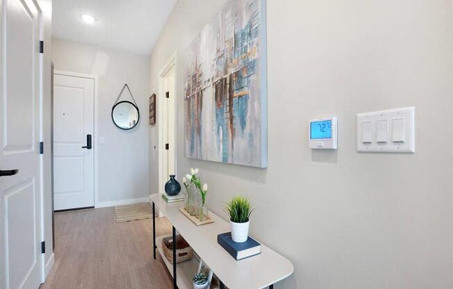 A hallway with a white table and a painting on the wall.