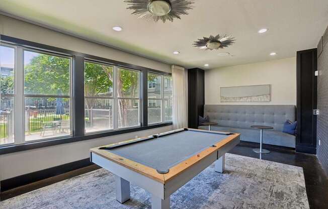 A pool table in a room with a view of the outside.