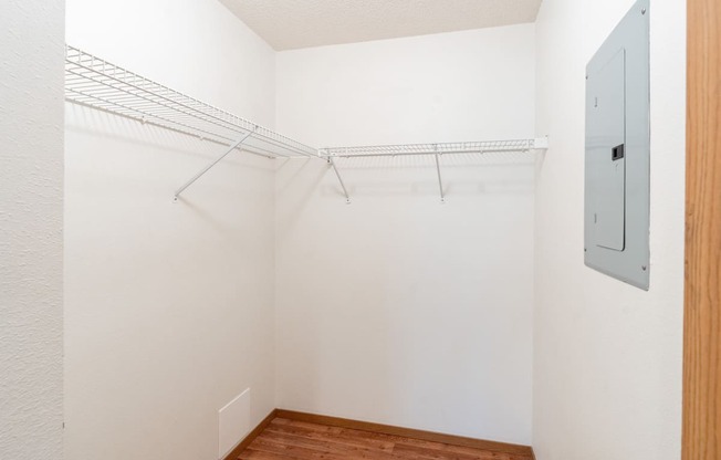 an empty closet with a metal rack on the wall and a wood floor. Fargo, ND Rosegate Apartments