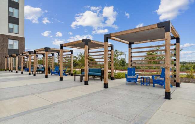 a row of wooden structures with blue chairs and tables on a sidewalk