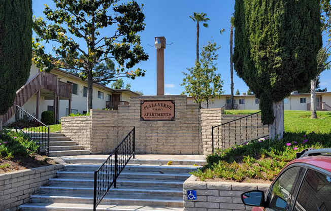 Parking lot steps to apartment walkways with mature landscaping and lots of grassy open space at Plaza Verde Apartments in Escondido, California.