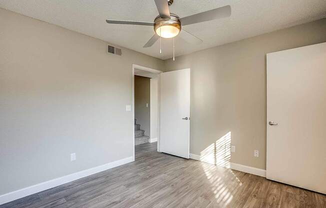 A room with a ceiling fan and light, hardwood floors, and white walls at Sterling Point Apartment Homes, Arizona