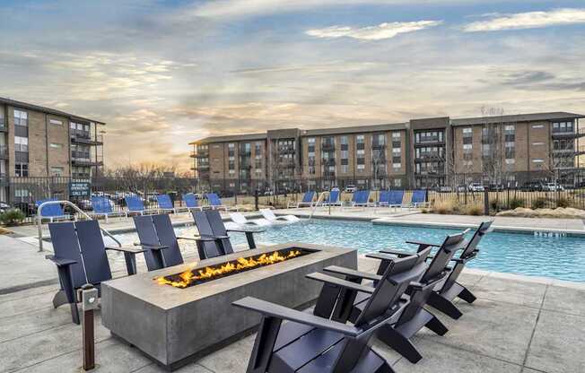 A fire pit sits in the middle of a pool surrounded by chairs.