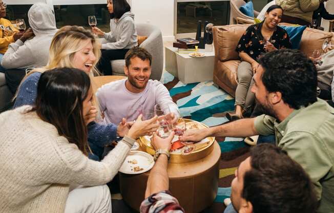 a group of people sitting around a table eating food and drinking wine