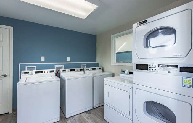 Laundry room showing new white washers and dryers and blue walls at The Lakes Apartments, Moses Lake, WA.