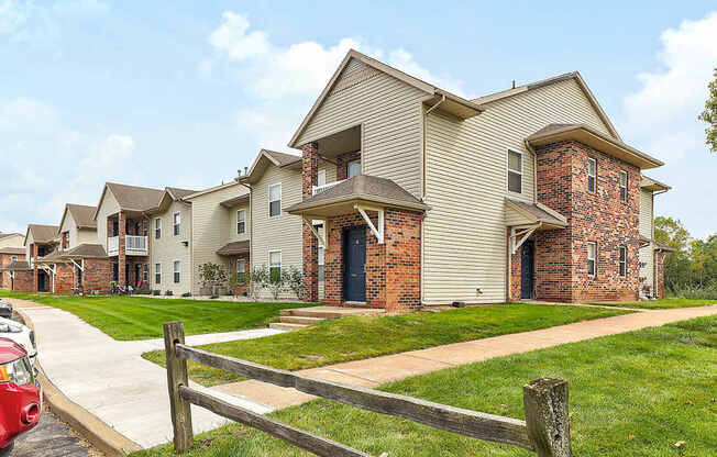 A red car is parked on a driveway in front of a house.
