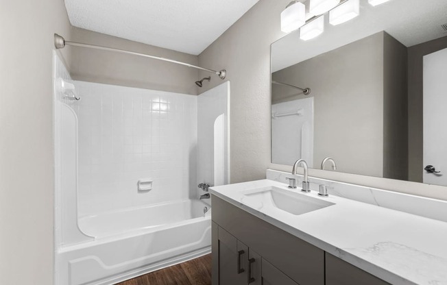 Renovated Bathroom with white quartz vanity, lighting and bath