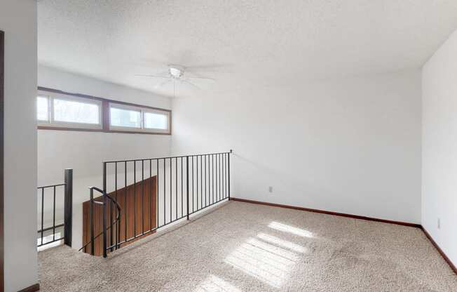 an empty living room with a balcony and a ceiling fan