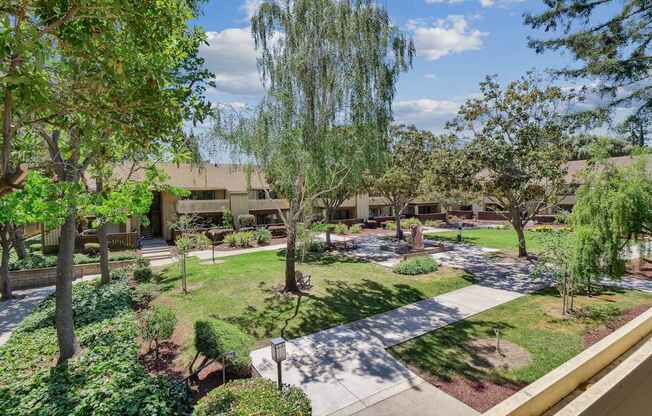 a courtyard with trees and grass and a building in the background at Summerwood Apartments, California