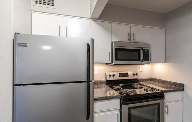 a kitchen with white cabinets and stainless steel appliances and a refrigerator