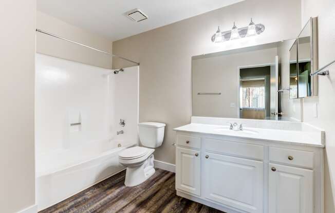 a bathroom with a toilet sink mirror and bathtub at Redlands Park Apts, Redlands, 92373