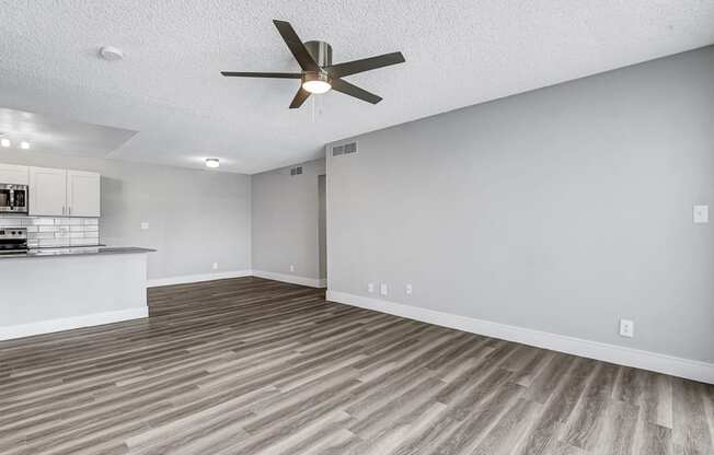 an empty living room with a ceiling fan