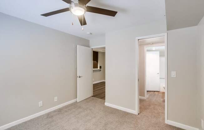 A room with a ceiling fan and two open doors.
