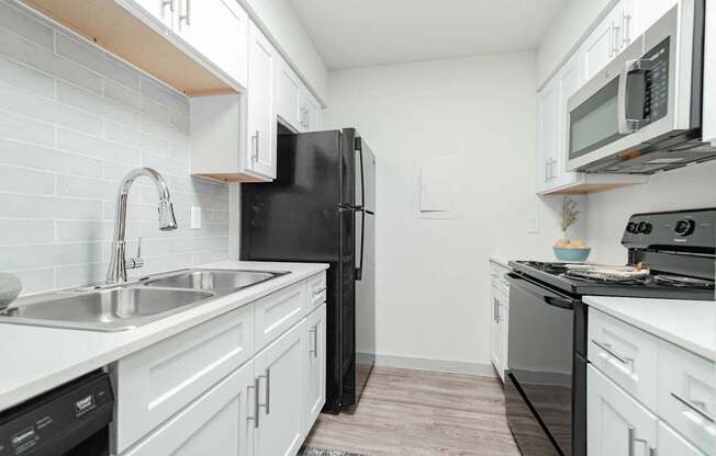 A kitchen with black appliances and white cabinets.