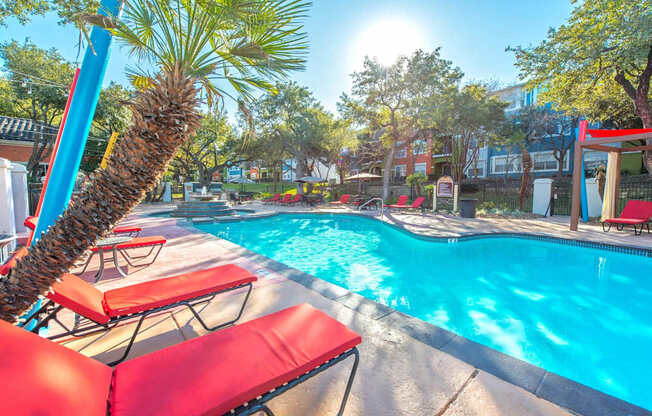 A pool with red chairs and a palm tree at Reserve at Canyon Creek,San Antonio, Texas