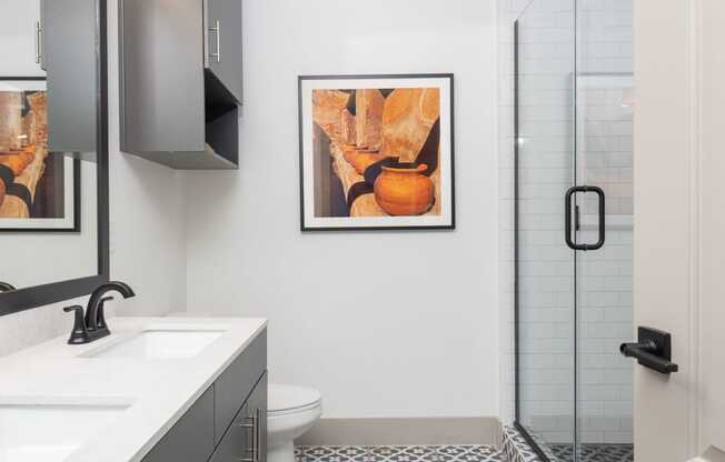 A bathroom with a toilet, sink, and a patterned tile floor.