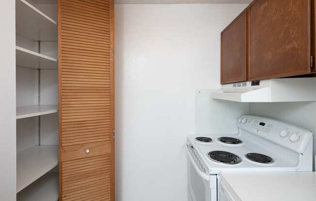 a kitchen with a white stove and a wooden cabinet