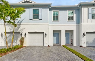 Boatman Hammock Townhomes in Lake Worth, FL photo of  a white house with two garage doors and a driveway