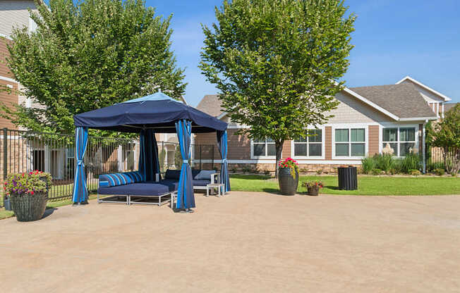 A blue canopy pavilion is situated in the middle of a paved area.