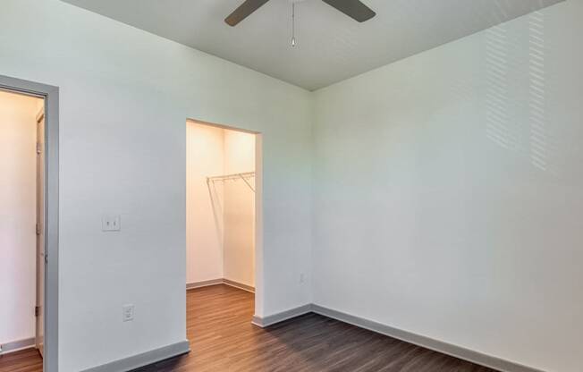 a room with white walls and wood floors and a closet