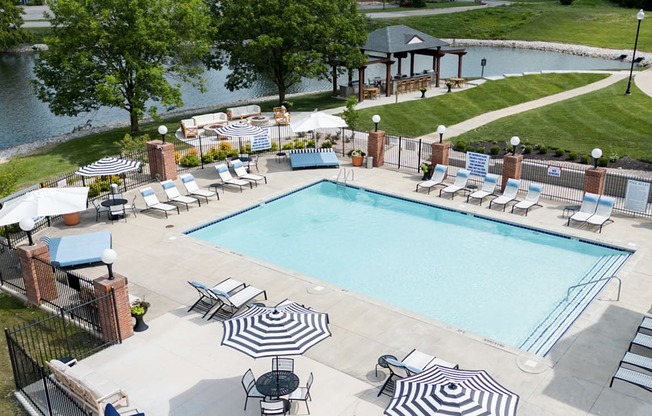 A large outdoor swimming pool surrounded by lounge chairs and umbrellas.