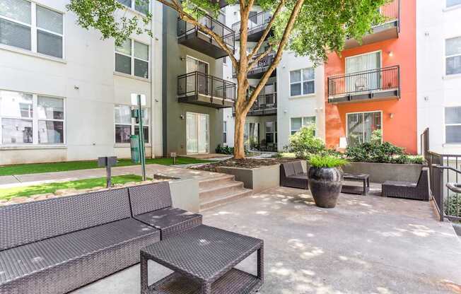 A patio with a couch, table, and potted plants.