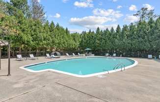 a swimming pool with chaise lounge chairs and trees in the background