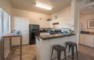 A kitchen with a black refrigerator and white cabinets at Autumn Oaks Apartments, Roseville, CA, 95678