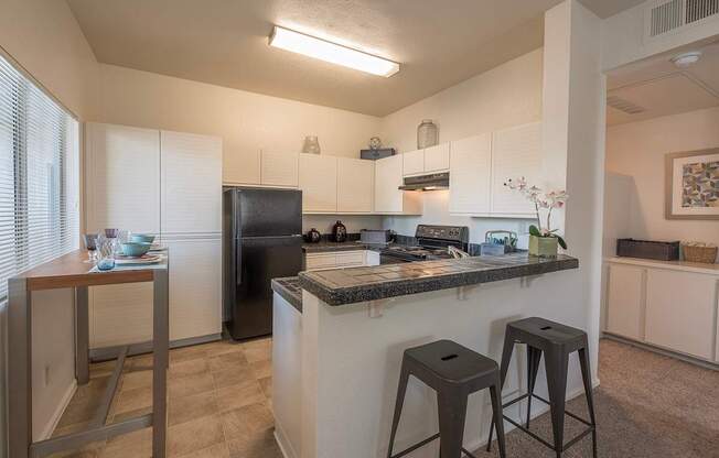 A kitchen with a black refrigerator and white cabinets at Autumn Oaks Apartments, Roseville, CA, 95678