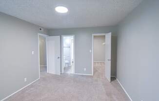 A room with carpeted floor and three open doors.