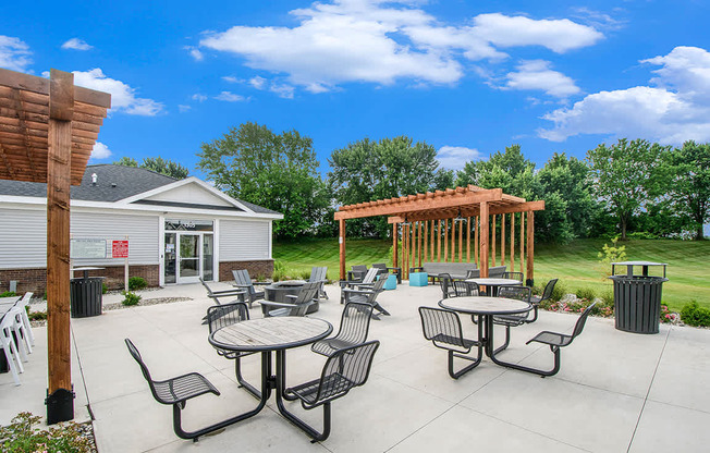 an outdoor patio with pergolas, a fire pit, tables and chairs at The Crossings Apartments, Michigan, 49508