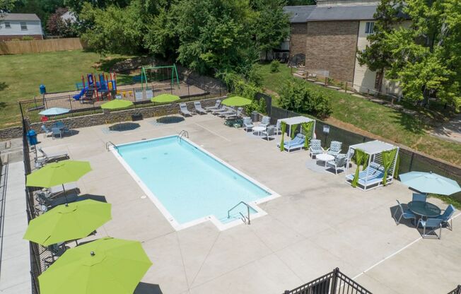 a swimming pool with lounge chairs and umbrellas in front of a brick building at Stonewater Apartments, Louisville, KY 40241