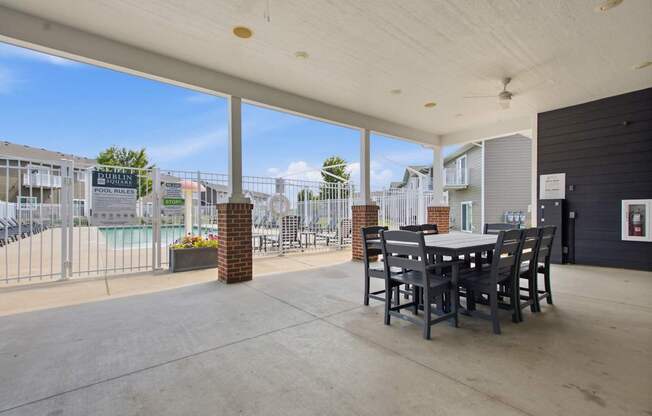 A patio with a table and chairs overlooking a pool.