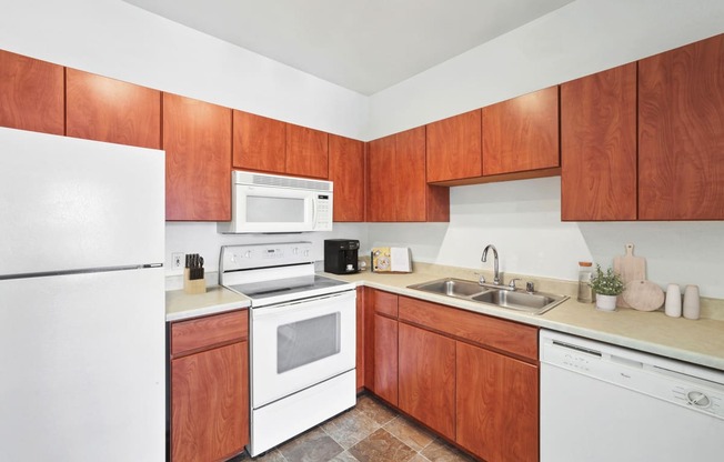 kitchen with white appliances, wood cabinetry, and tile flooring