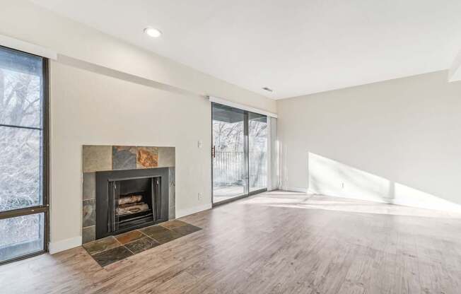 A large, empty room with a fireplace and wood flooring.