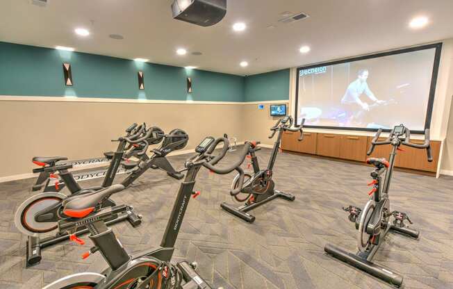 a gym with exercise bikes and a screen on the wall  at Pinnacle Apartments, Jacksonville, 32256